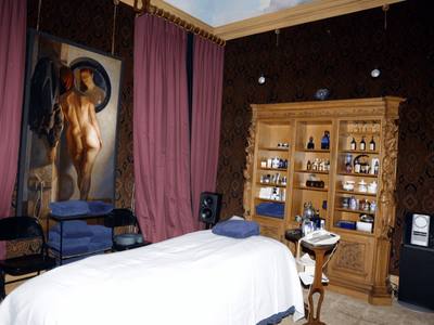 File:EFTA00000164 - Luxurious spa room with a massage bed ornate wooden cabinet filled with toiletries and a large painting on the wall.jpg