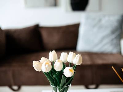 File:Decorative arrangement of tulips in clear vase on table next to brown sofa in modern living room setting.jpg