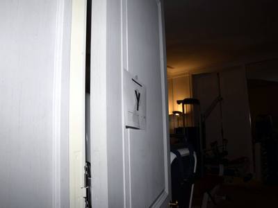 File:EFTA00000255 - Partially open white door reveals a dimly lit gym space with exercise equipment visible through the opening.jpg