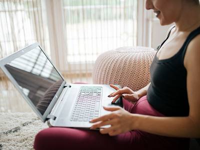 File:A woman in a black tank top sits on a soft floor, focusing on her laptop.jpg