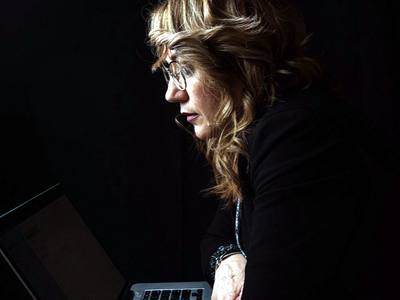File:A woman sits at a desk with her laptop, deeply focused on her work in a low-light environment.jpg