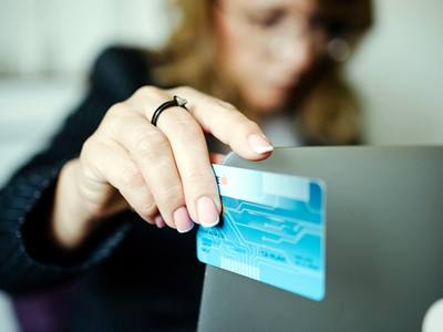 File:A woman sits comfortably at her laptop, holding her credit card up for an online transaction.jpg