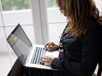 File:A woman with long hair sits comfortably in a chair, focused on her laptop.jpg