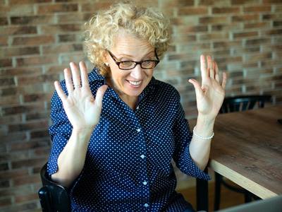 File:Cheerful woman smiling and making gestures with her hands while talking on a video call on her laptop.jpg